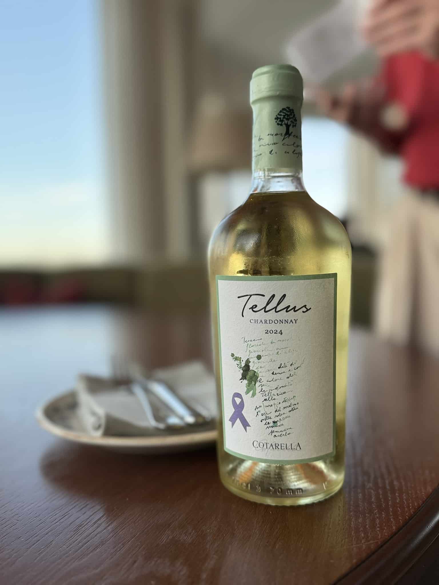Flaske Tellus Chardonnay 2024 fra Cotarella på træbord ved vindue