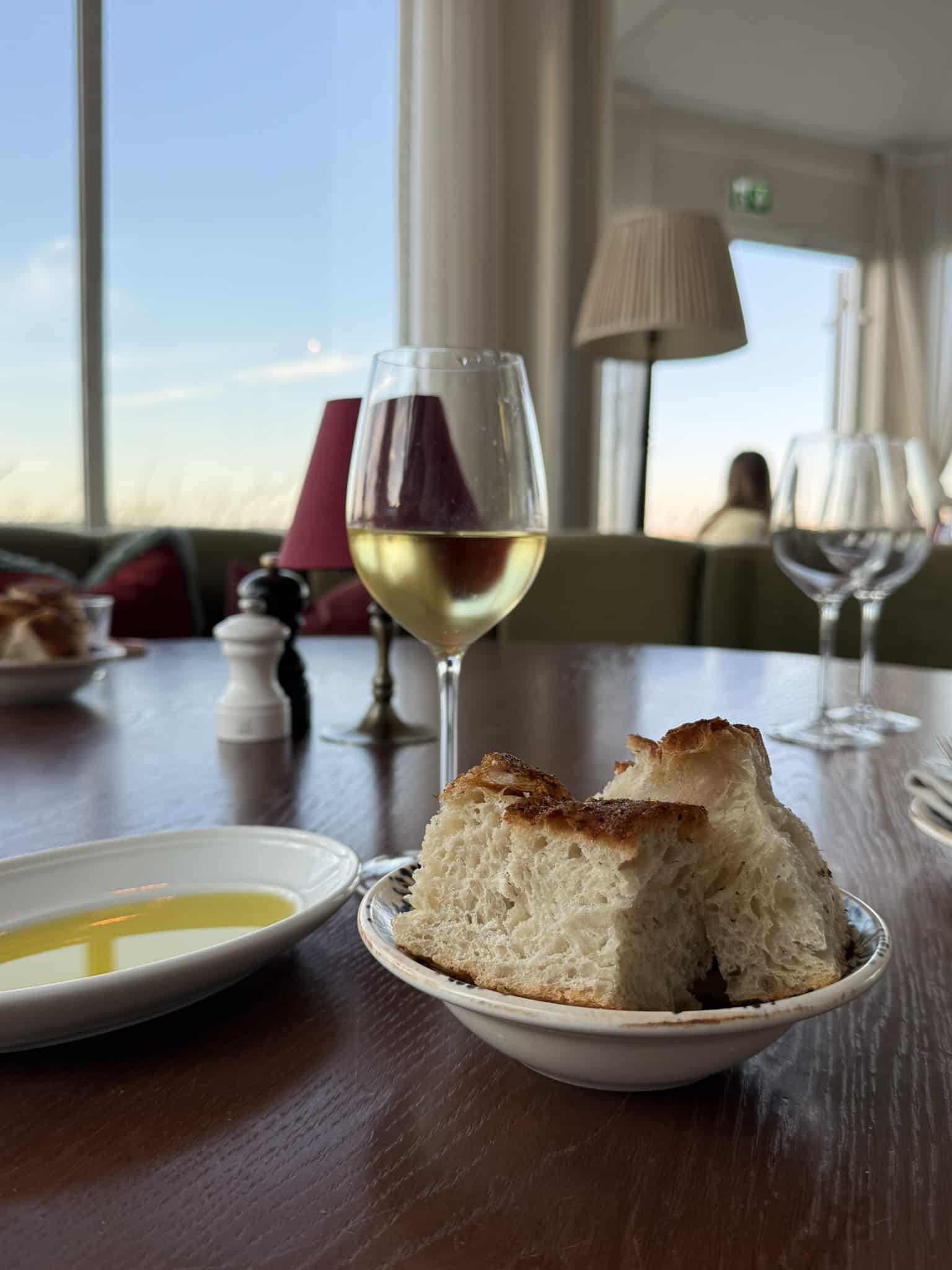 Skål med focaccia-brød, olivenolie i skål og glas hvidvin