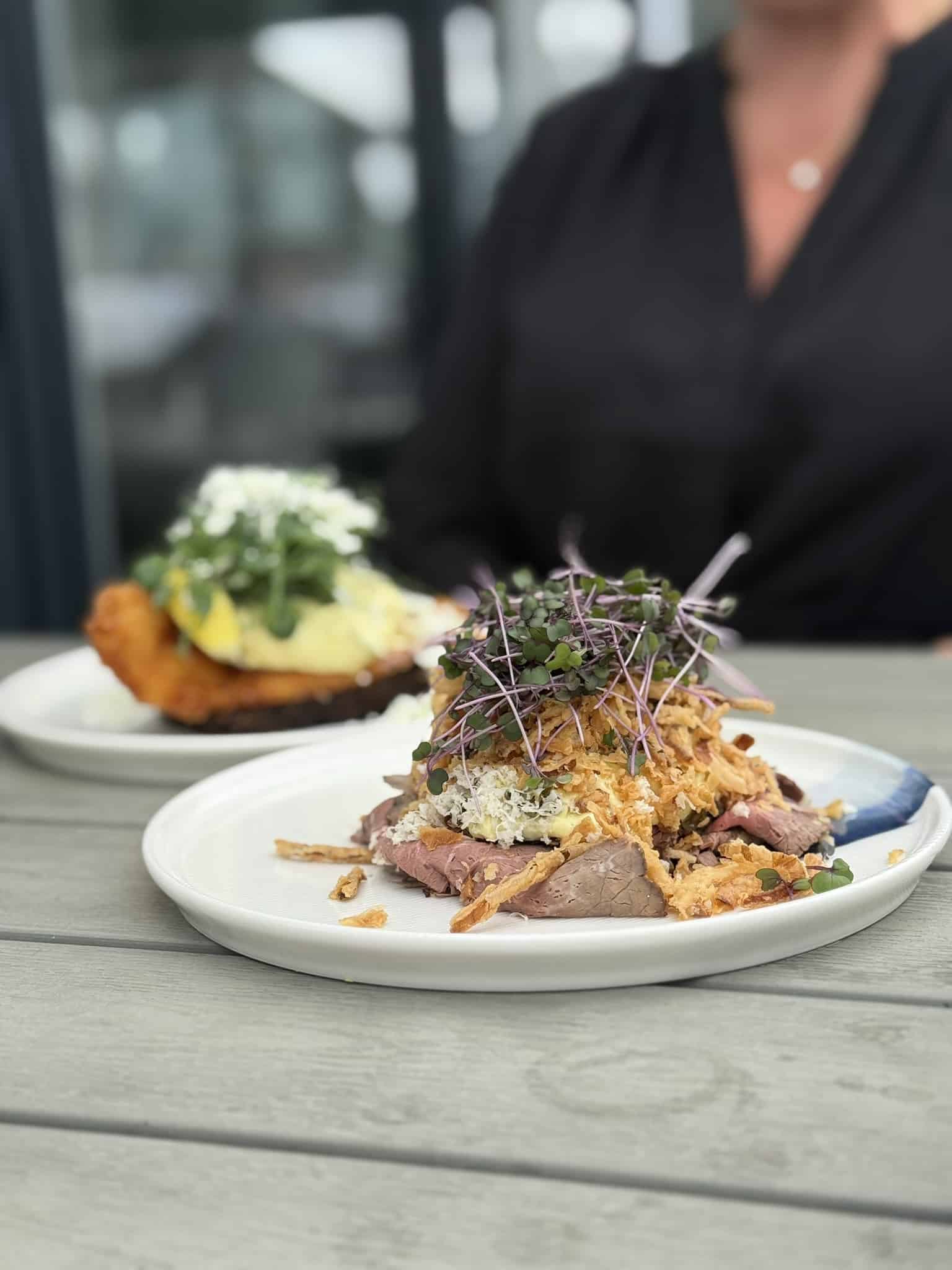 Smørrebrød med roastbeef, ristede løg og mikrogrønt, fiskefilet bagved