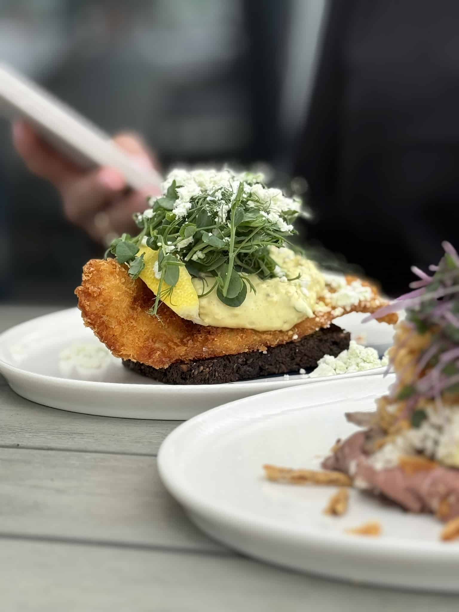 Paneret fiskefilet på rugbrød med remoulade, citron og ærteskud