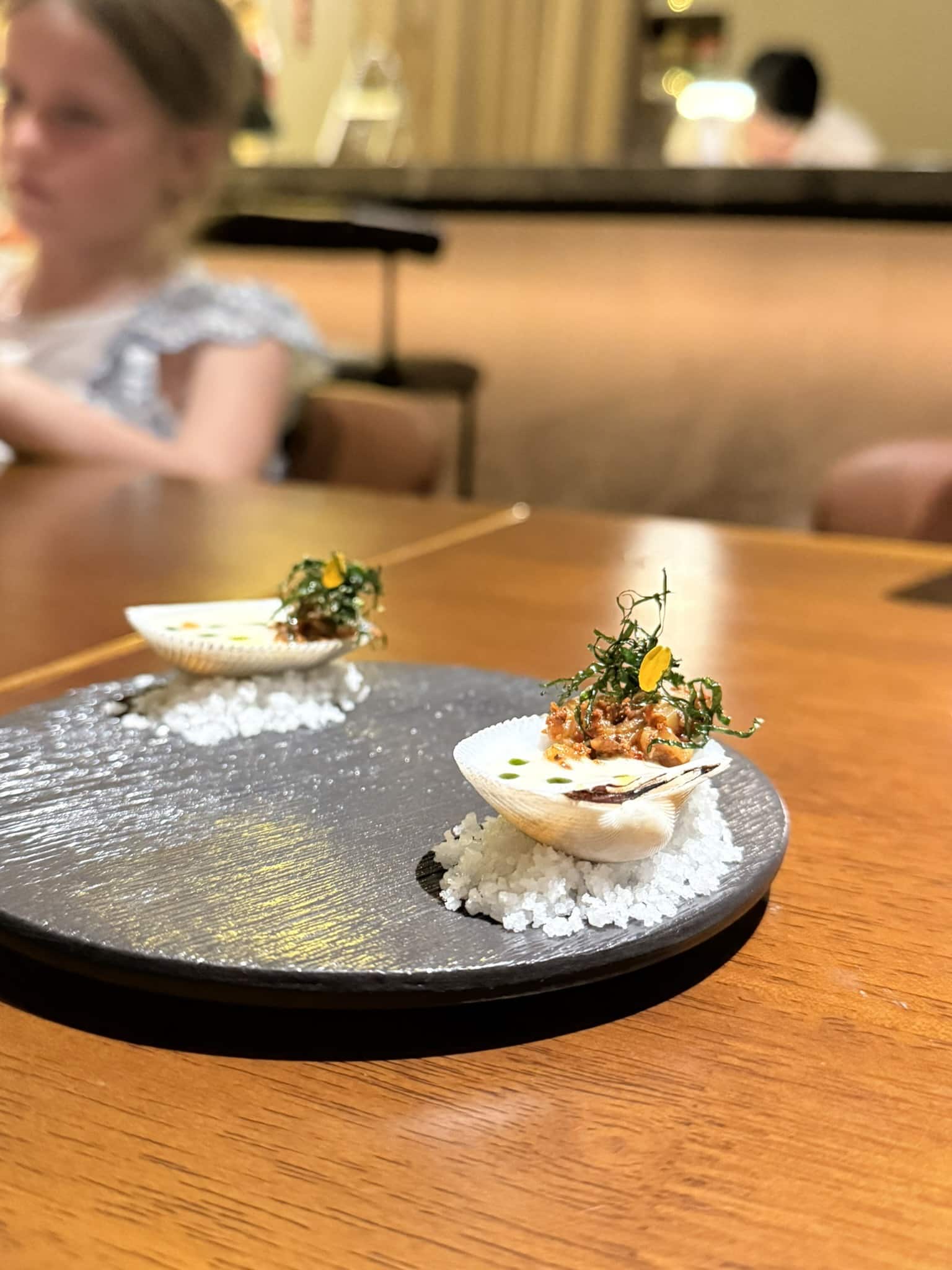 To muslingeskaller med cremet fyld og urter serveret på groft salt