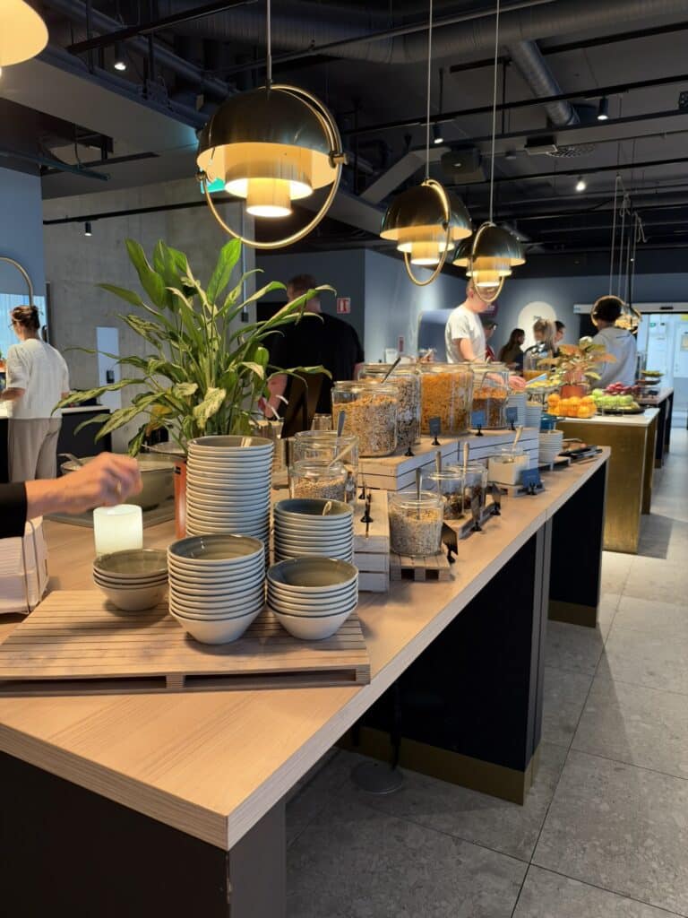 Morgenmadsbuffet med stablede skåle, glasbeholdere med müsli og gæster
