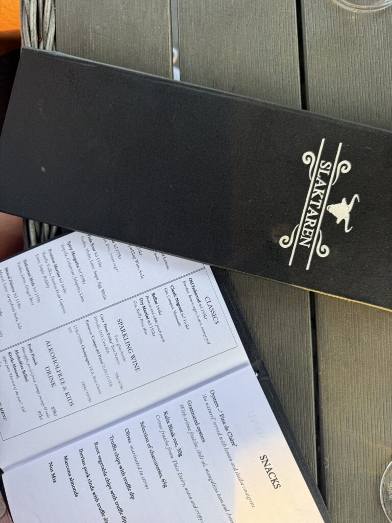 Sort menukort fra Slaktaren opslået på bord med drinks og snacks