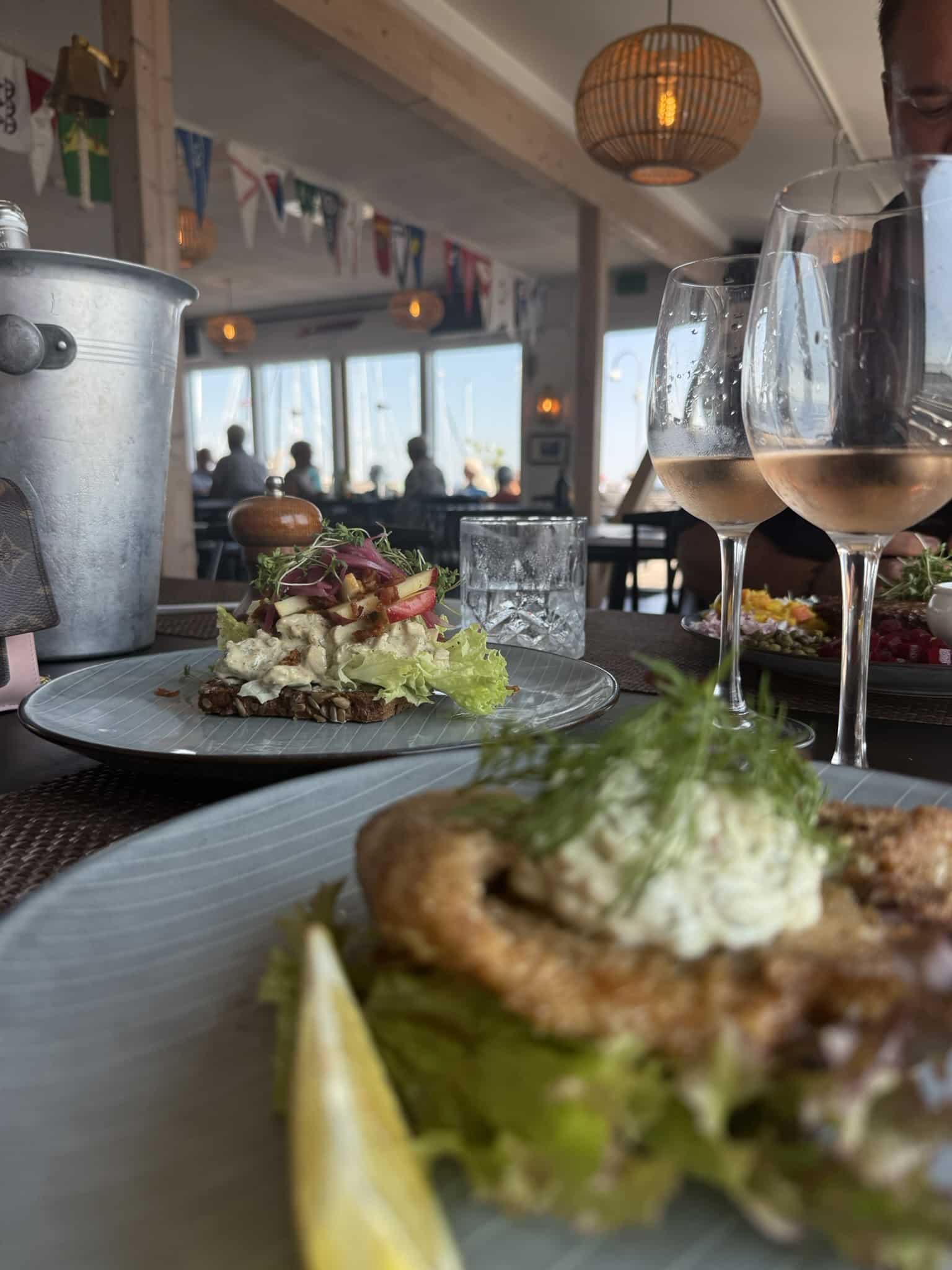 Smørrebrød med hønsesalat og paneret fiskefilet, to glas rosévin