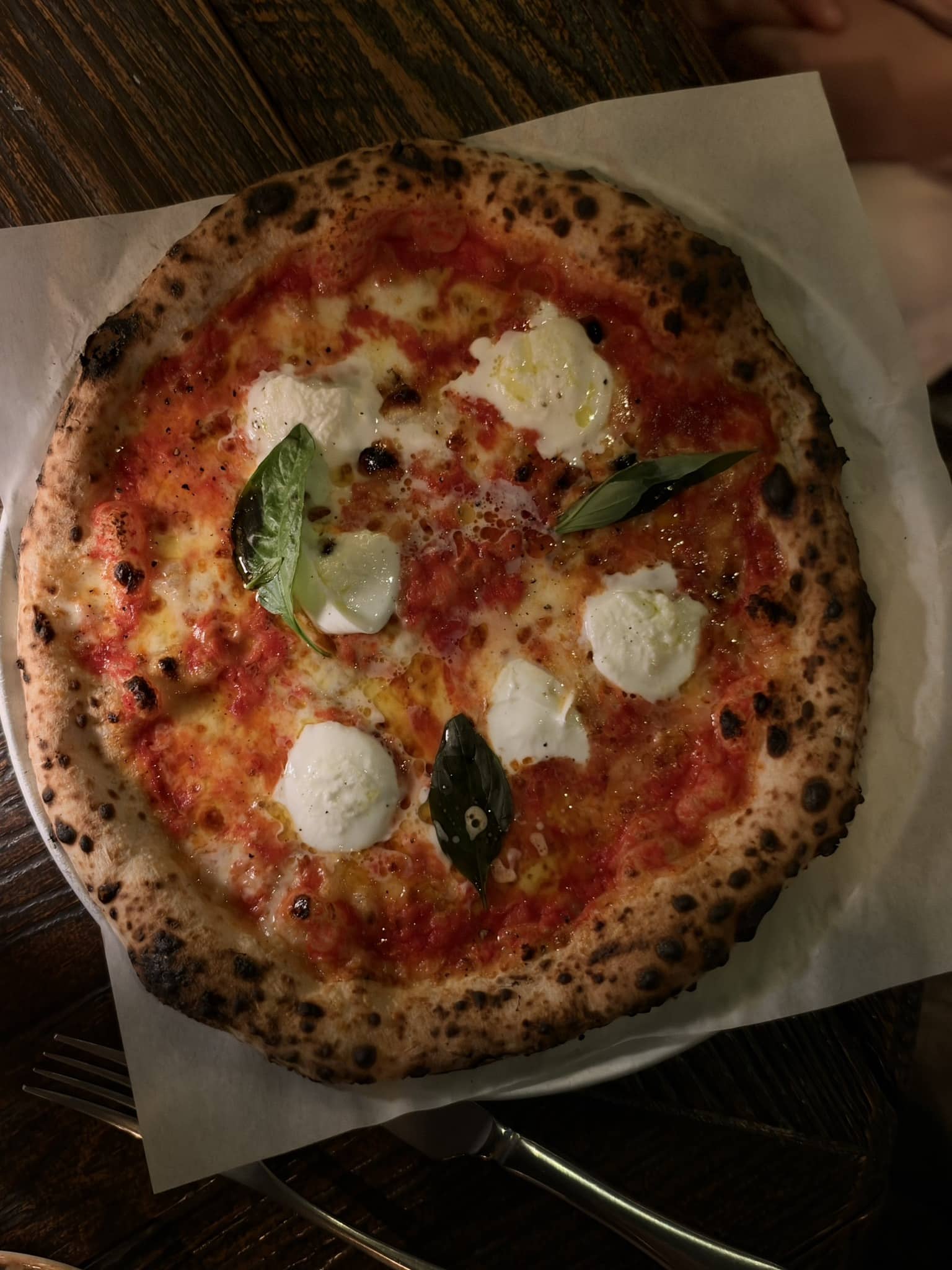 Pizza margherita med tomatsauce, mozzarella og basilikum på bagepapir.