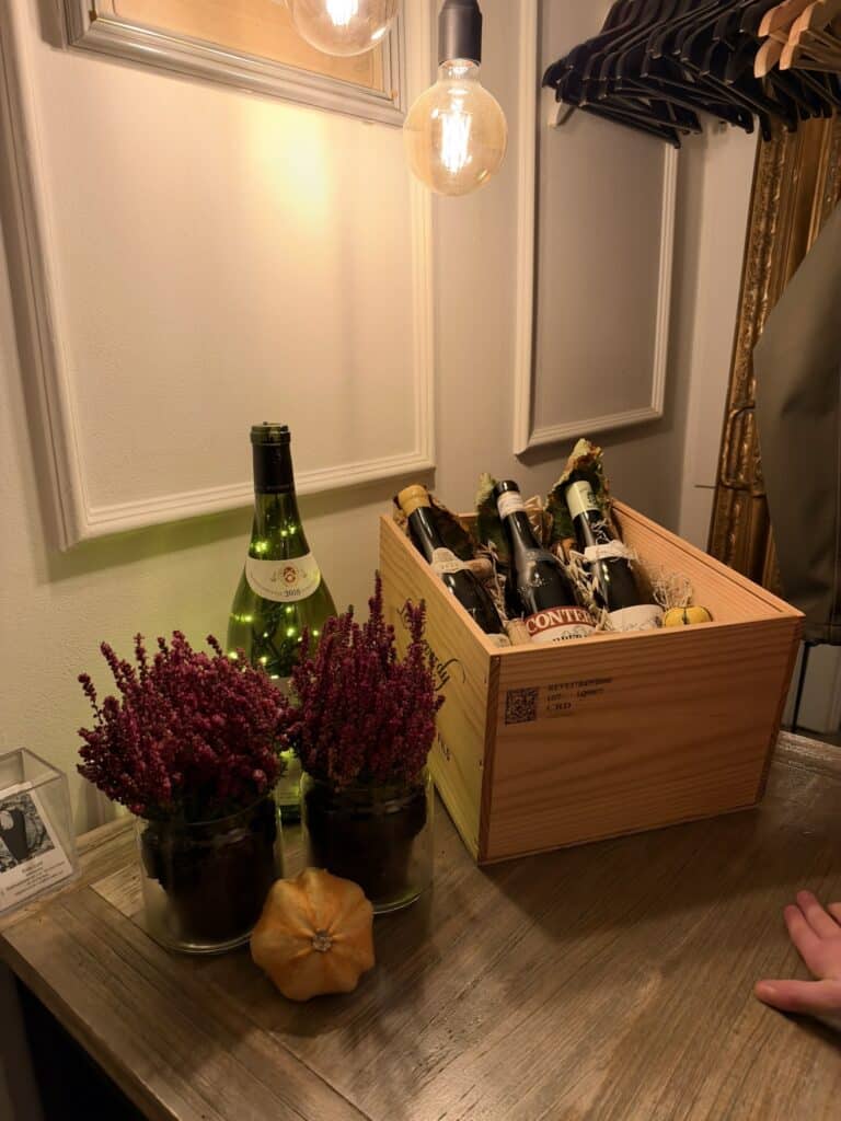 Trækasse med vinflasker, lyngplanter og lille græskar på bord