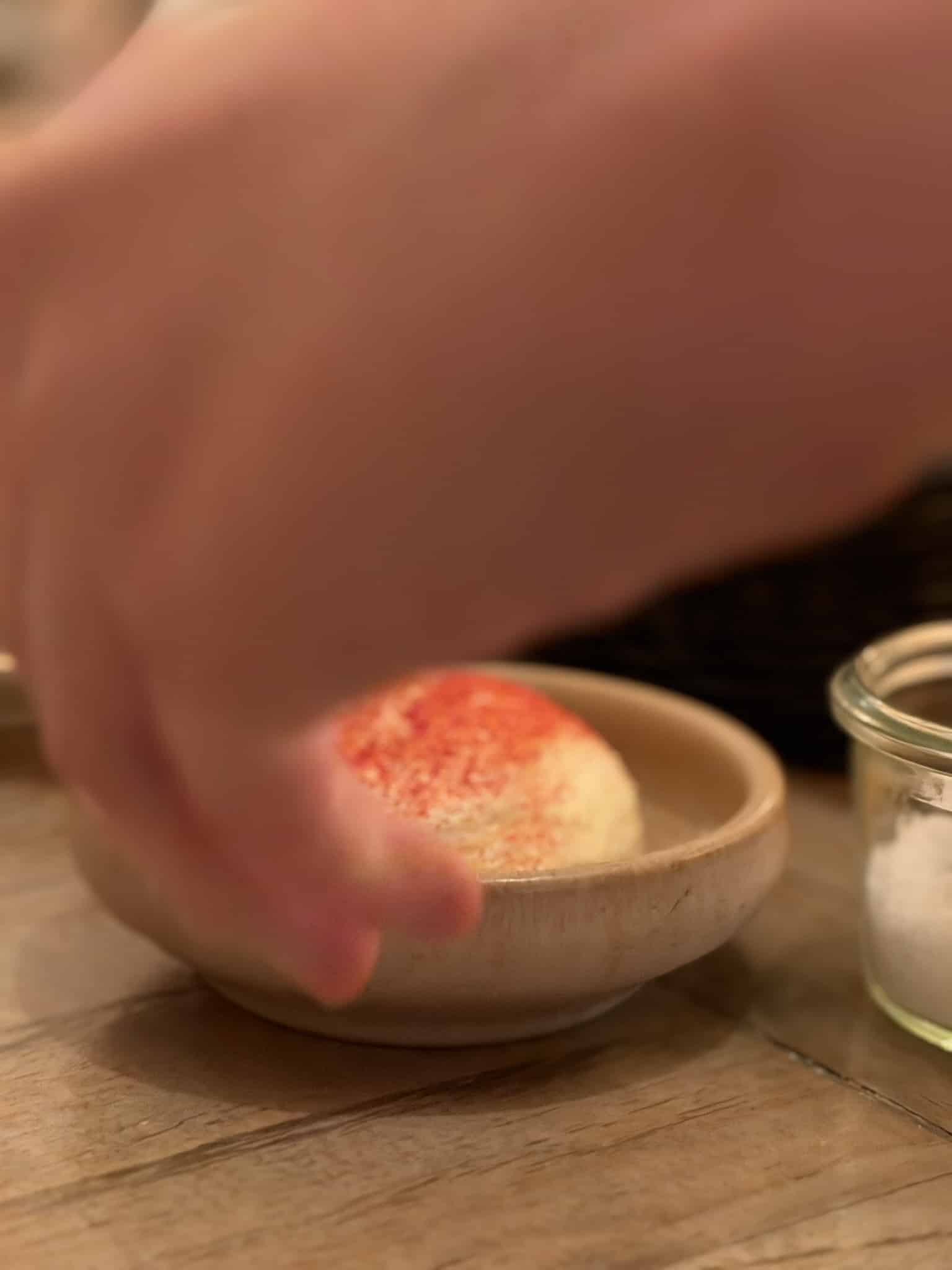 Hånd rækker efter kugle smør drysset med rødt pulver