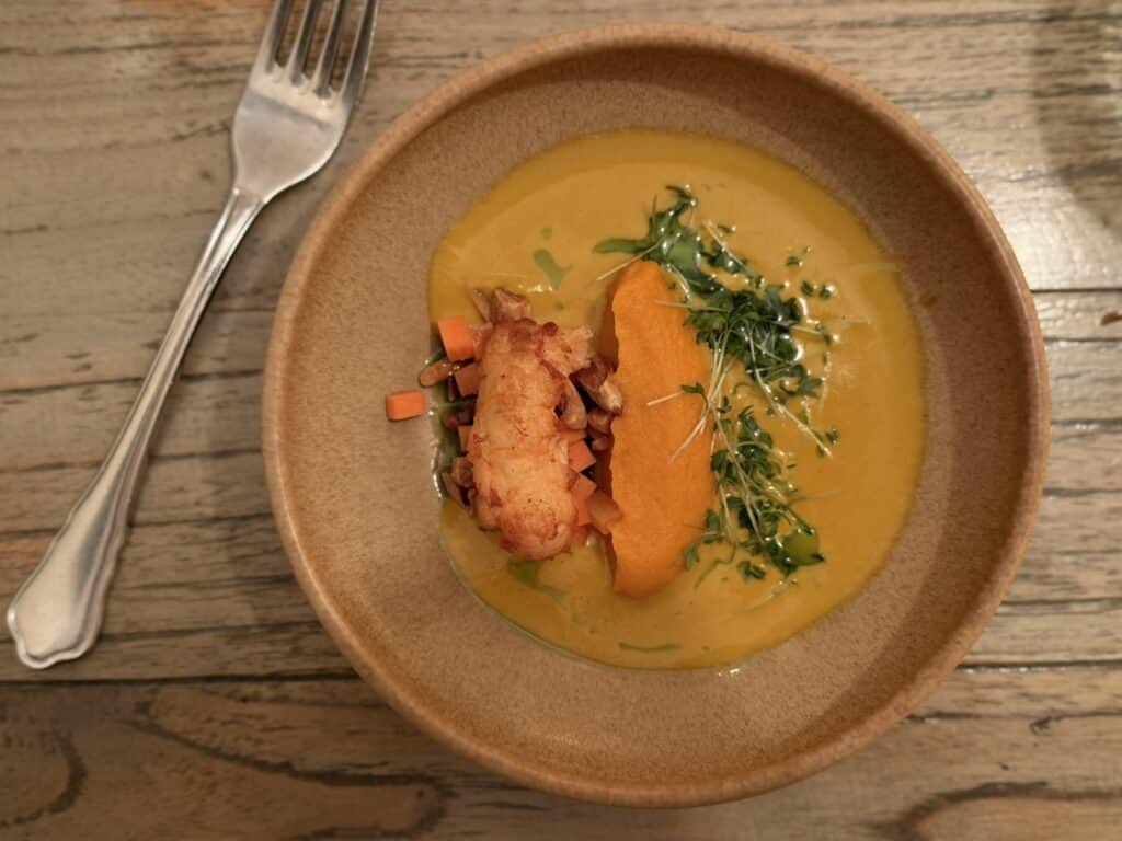 Gul suppe set ovenfra med skaldyr, gulerodspuré og karse