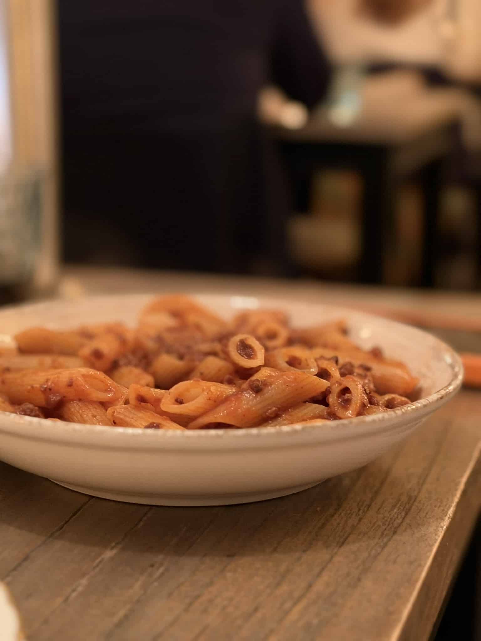 Dyb hvid tallerken med penne i tomatsauce med hakket kød