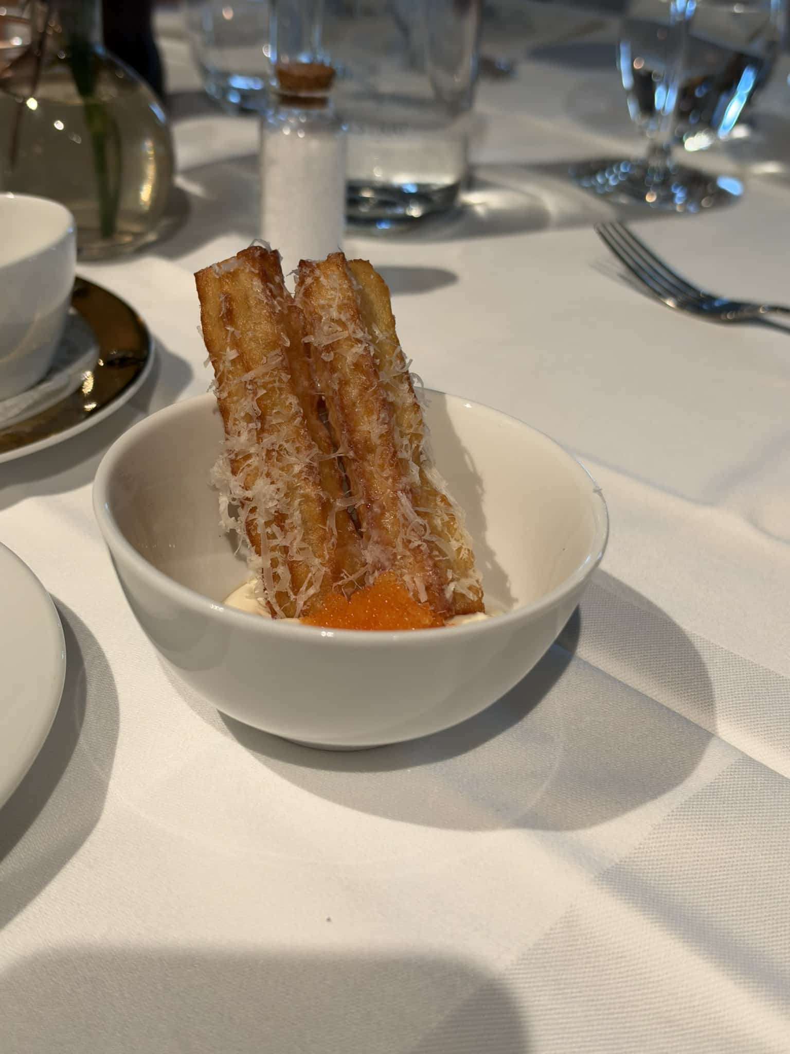 Friterede kartoffelstave med revet ost og rogn på creme i hvid skål