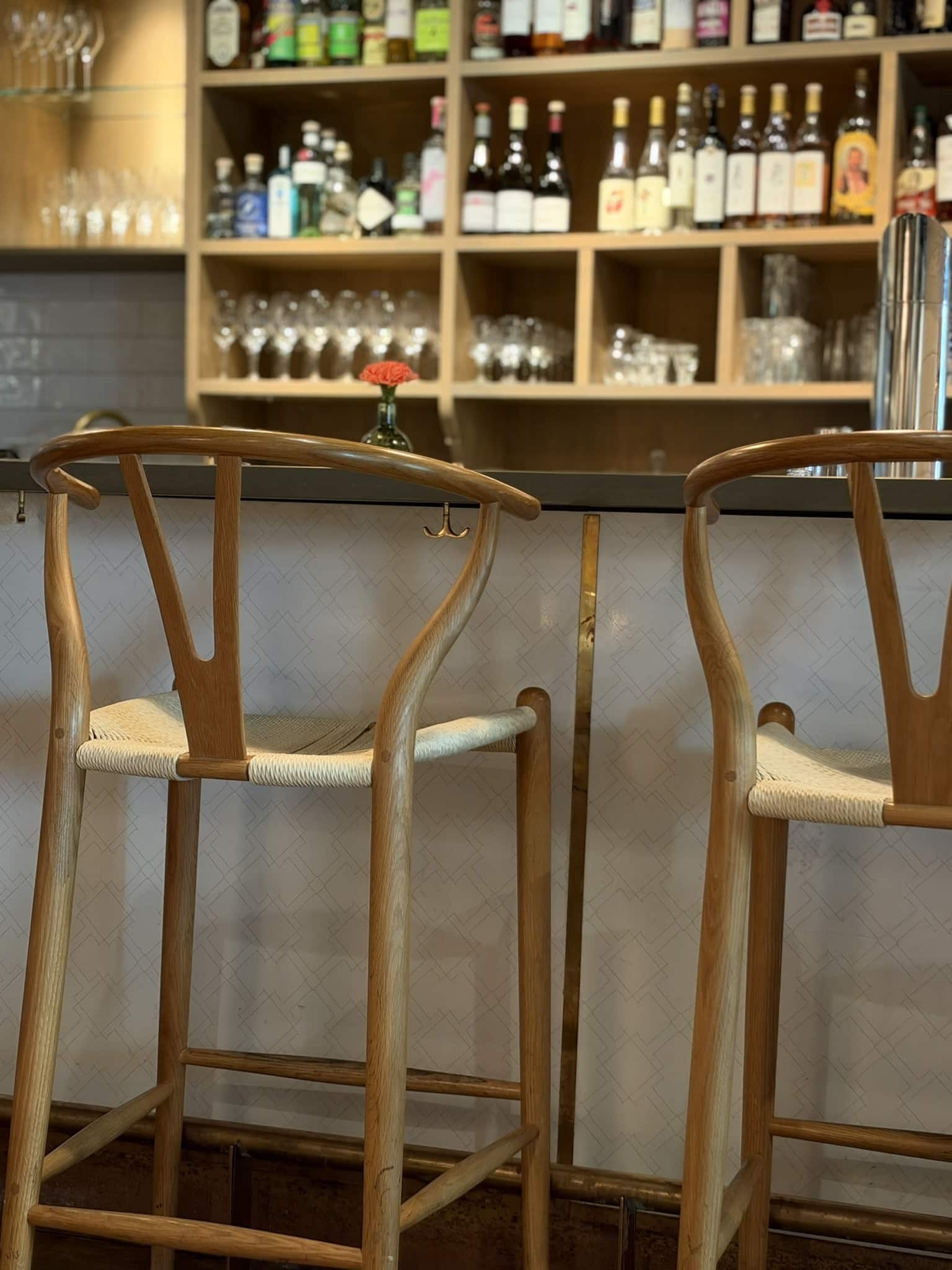 To Y-stole i træ ved bardisk med flasker og glas bagved