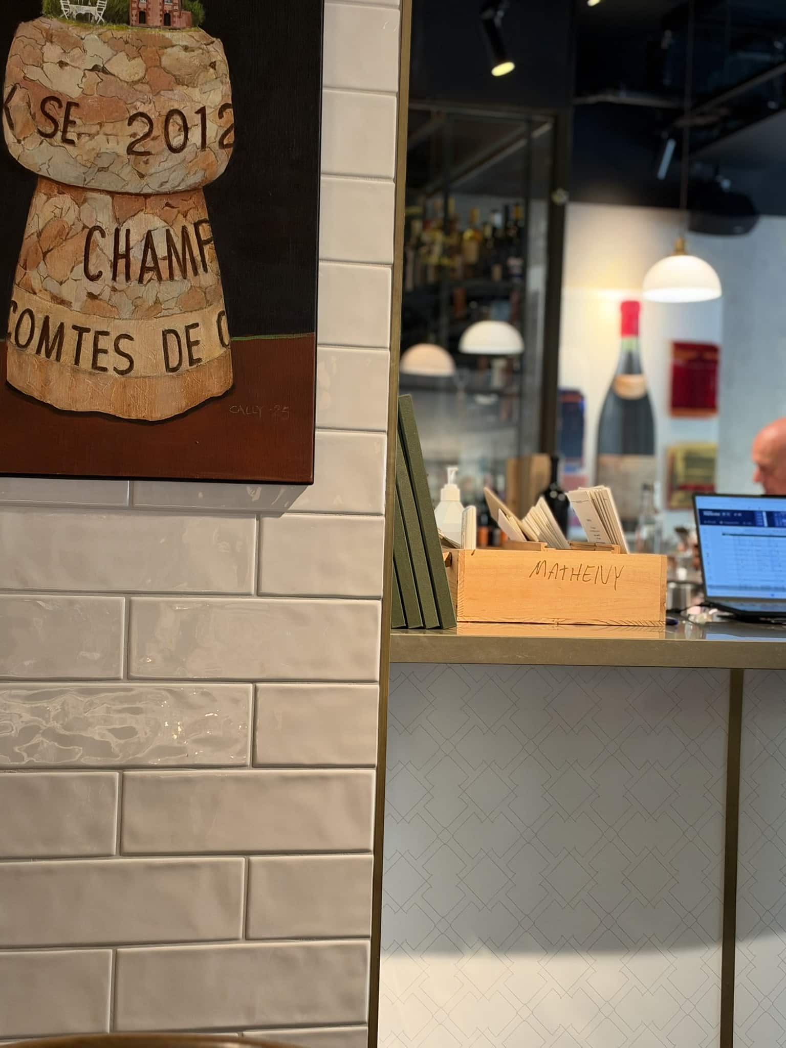 Maleri af champagneprop på flisevæg ved disk med laptop